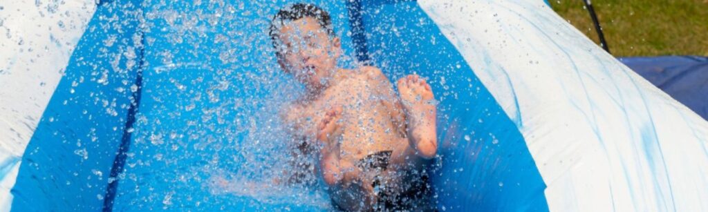 Child splashing down inflatable water slide