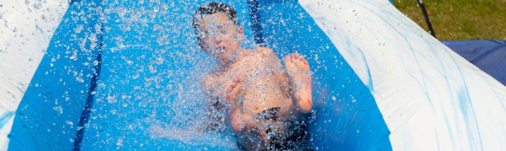 Child splashing down inflatable water slide